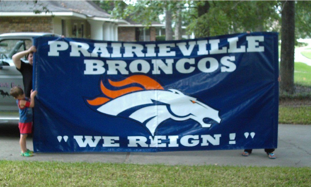 People holding a large blue Prairieville Broncos banner with the team logo and the slogan 