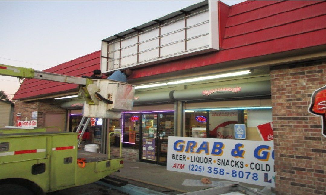 A worker in a lift truck repairs a sign for a 