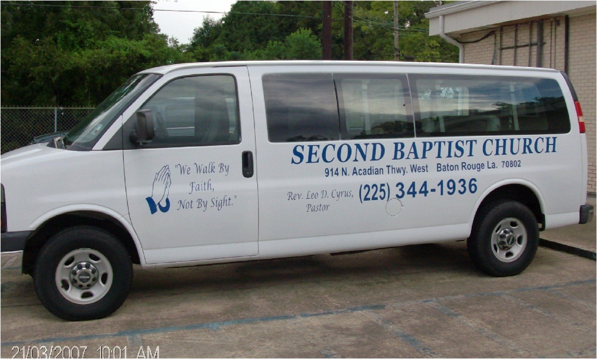 White Second Baptist Church van parked outdoors, with signage and phone number visible.