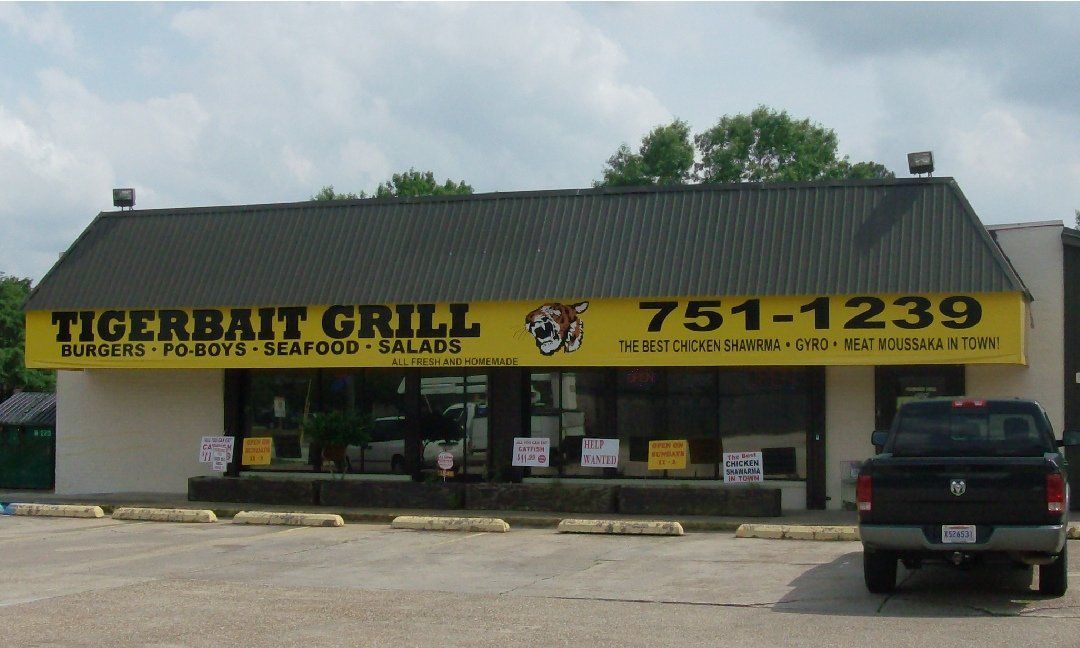Tigerbait Grill restaurant with a yellow sign and black pickup truck parked out front.