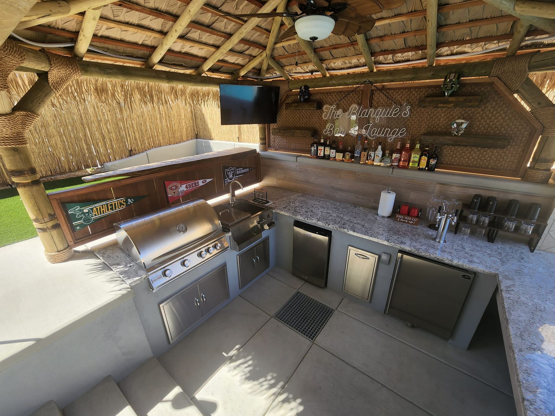 A tiki bar with a thatched roof and wooden stools