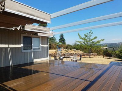 A wooden deck with a table and chairs on it in front of a house.