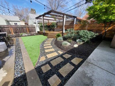 A backyard with a stone walkway leading to a pergola.