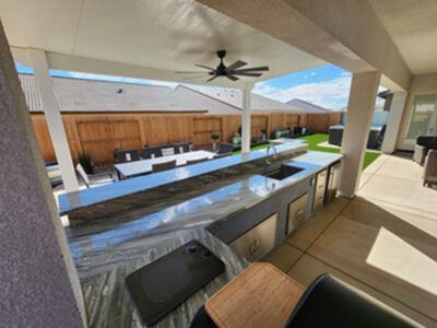 A large outdoor kitchen with a ceiling fan above it