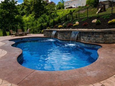 A large swimming pool with a waterfall in the backyard.