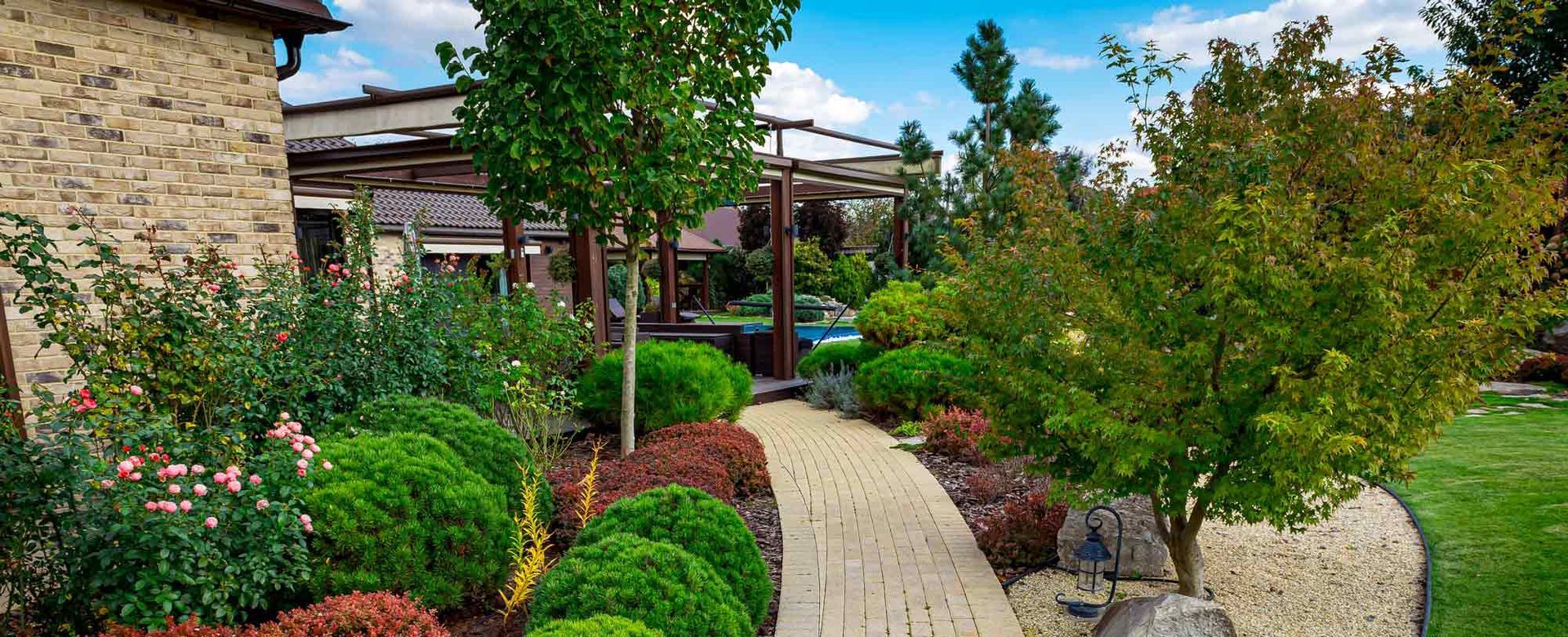 A brick walkway leading to a house surrounded by trees and bushes.