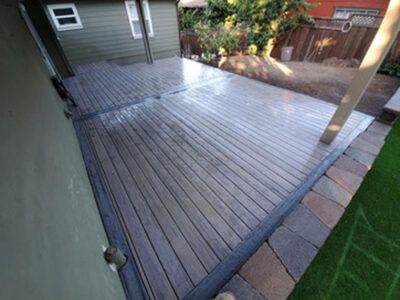 A large wooden deck in the backyard of a house.
