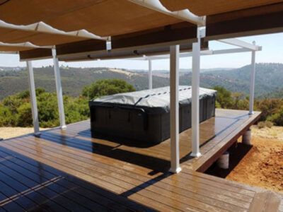 A hot tub is sitting on a wooden deck under a canopy
