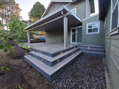 A house with a covered deck and stairs in front of it.