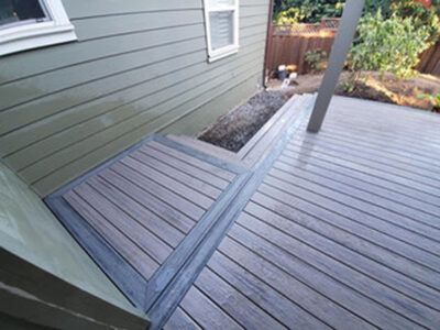 A wooden deck with stairs leading up to it next to a house.
