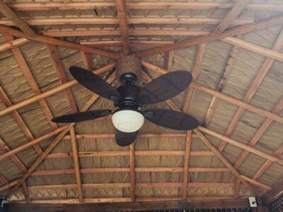 A ceiling fan is hanging from the ceiling of a gazebo.