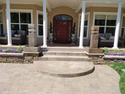 The front porch of a house with a red door and steps