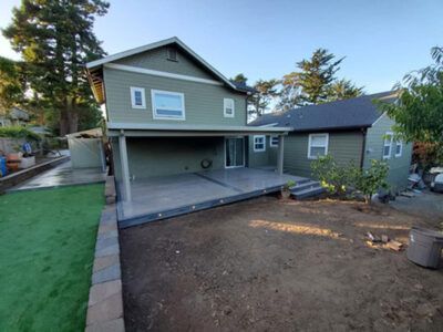 A large green house with a covered patio in the backyard.