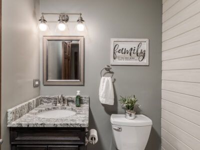 A bathroom with a sink , toilet , mirror and a sign that says `` family ''.