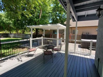 There is a table and chairs on the deck with a pergola.