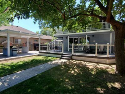 The backyard of a house with a large deck and covered porch.