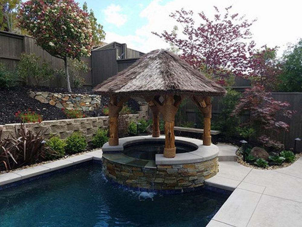 A gazebo over a pool with a thatched roof
