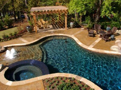 An aerial view of a large swimming pool with a hot tub and a pergola.