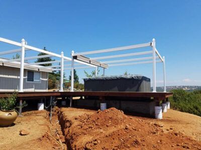 A hot tub is sitting on top of a wooden deck next to a house.
