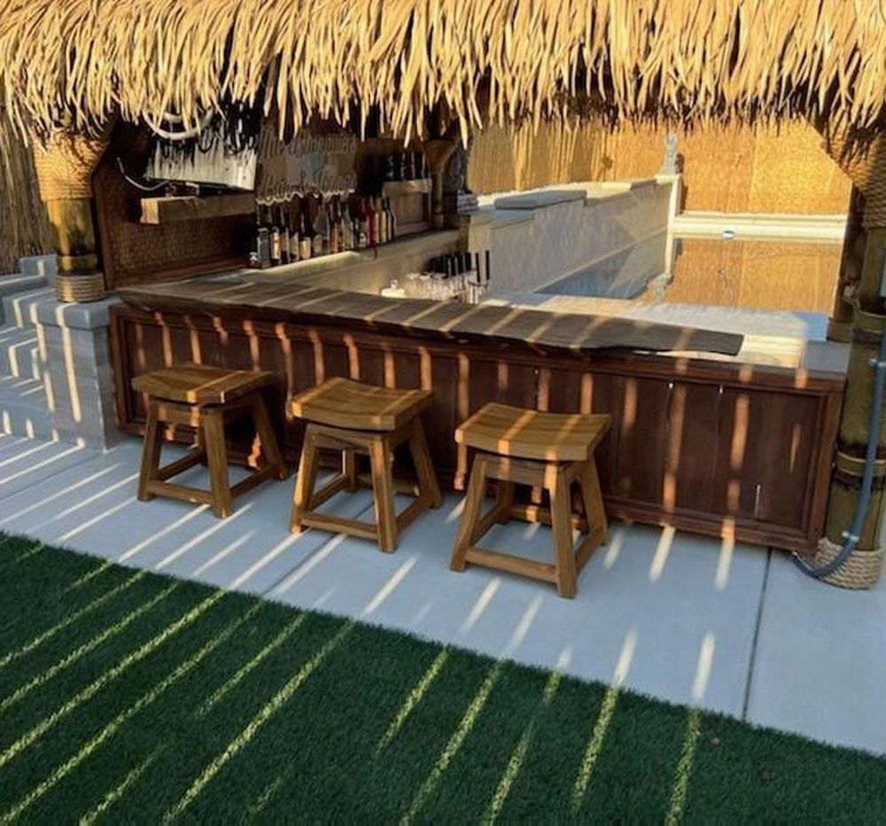 A tiki bar with a thatched roof and wooden stools
