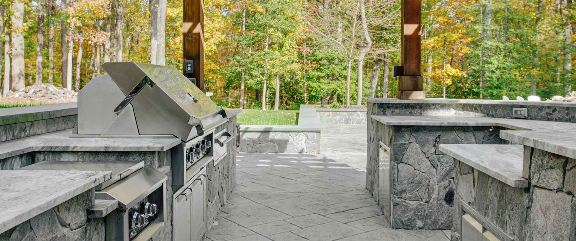 A large outdoor kitchen with stainless steel appliances and granite counter tops.