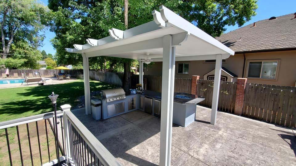 A backyard with a pergola and a grill.