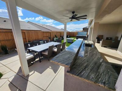 A patio with a table and chairs and a ceiling fan.