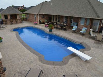 A large swimming pool is in the backyard of a house.