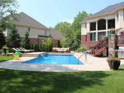 There is a large swimming pool in the backyard of a house.
