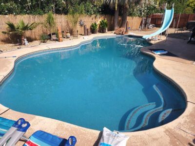 A large swimming pool with a slide in the backyard