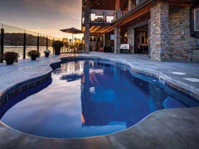 There is a large swimming pool in the backyard of a house.