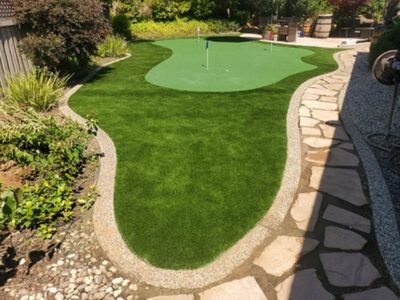 A putting green in a backyard with a stone walkway