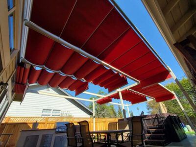 A red awning is covering a patio with a table and chairs.