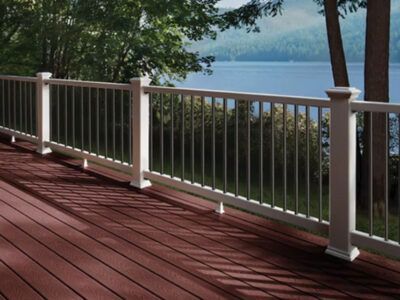 A wooden deck with a white railing overlooking a lake.