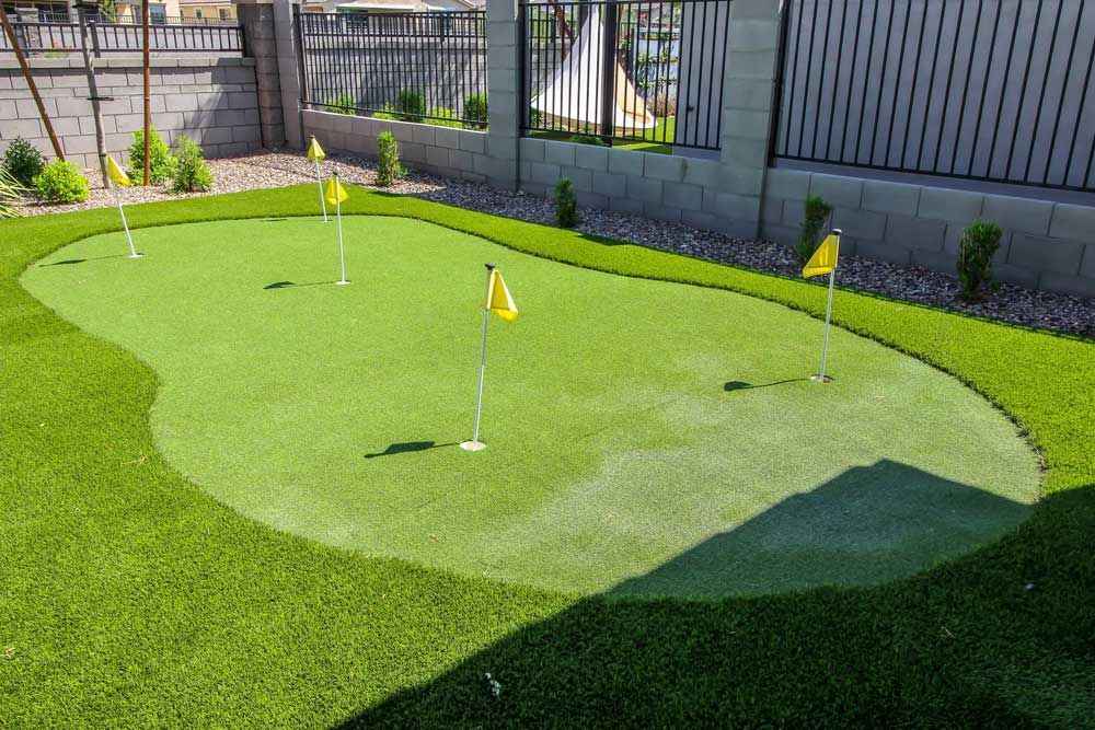 A green putting green with yellow flags on it