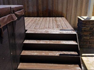 A wooden deck with stairs leading up to a hot tub.