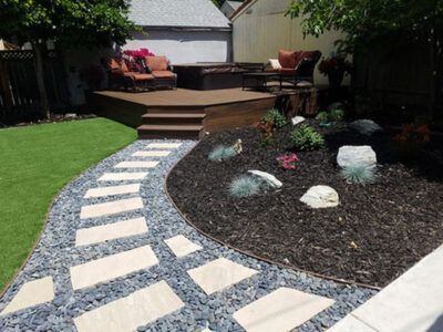A walkway leading to a deck in a backyard