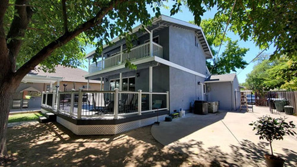 A house with a large deck and a tree in front of it.