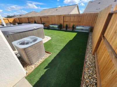 A backyard with a hot tub , air conditioner , and a fence.