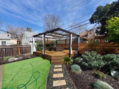 A backyard with a wooden deck and a pergola.
