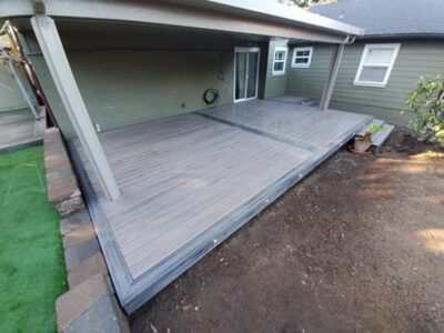 A large deck with a covered patio in the backyard of a house.