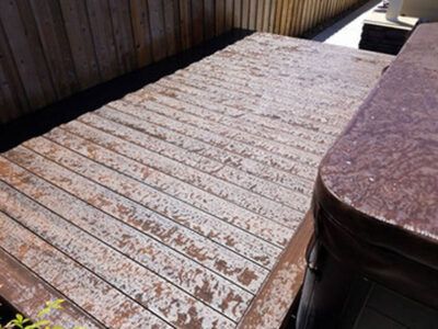 A wooden deck with a hot tub in the background