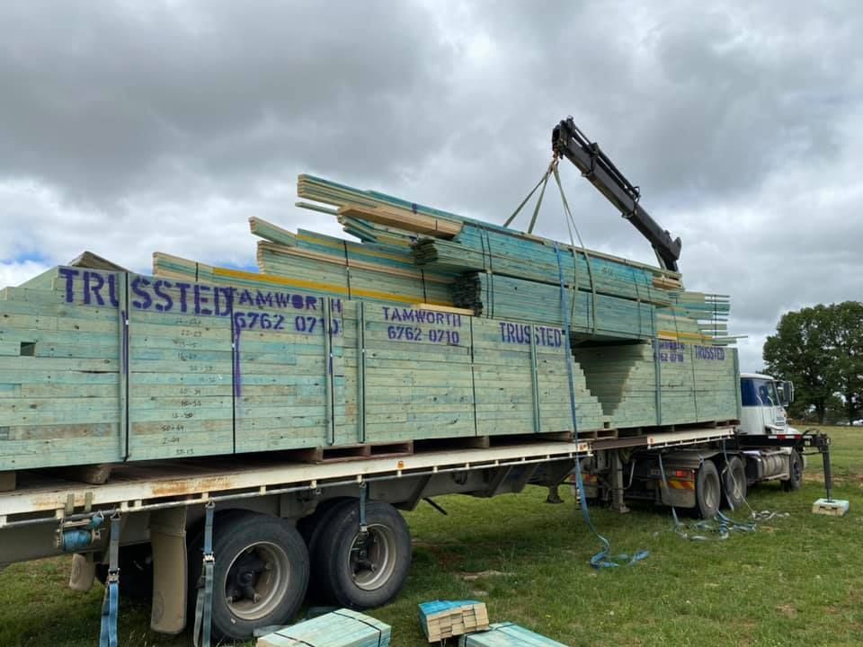 A Wooden Roof is Being Built With a Blue Sky in the Background — Trussted Frames & Trusses In Taminda, NSW