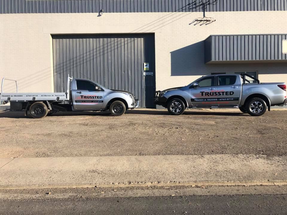 Two trucks are parked next to each other in front of a building — Trussted Frames & Trusses In Taminda, NSW