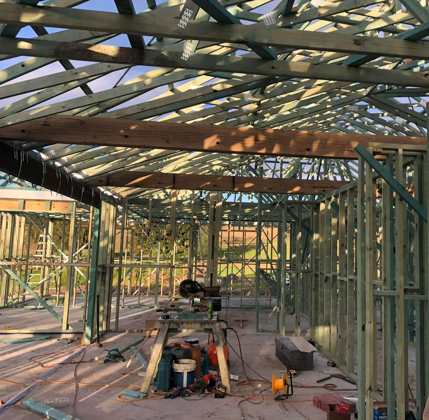 An empty room with wooden beams and a ceiling fan — Trussted Frames & Trusses In Taminda, NSW