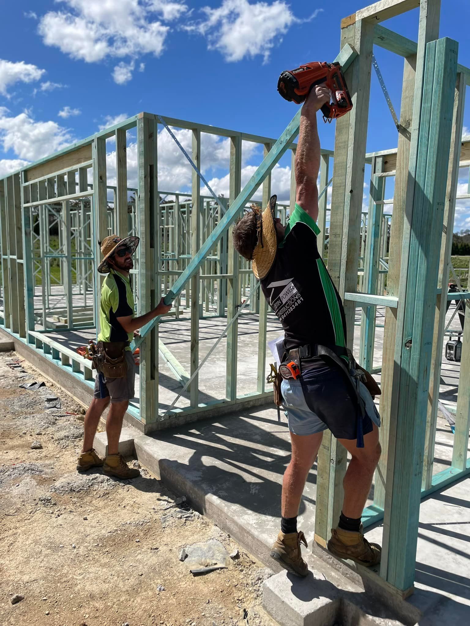 Two men working on a house frame on a construction site — Trussted Frames & Trusses In Taminda, NSW