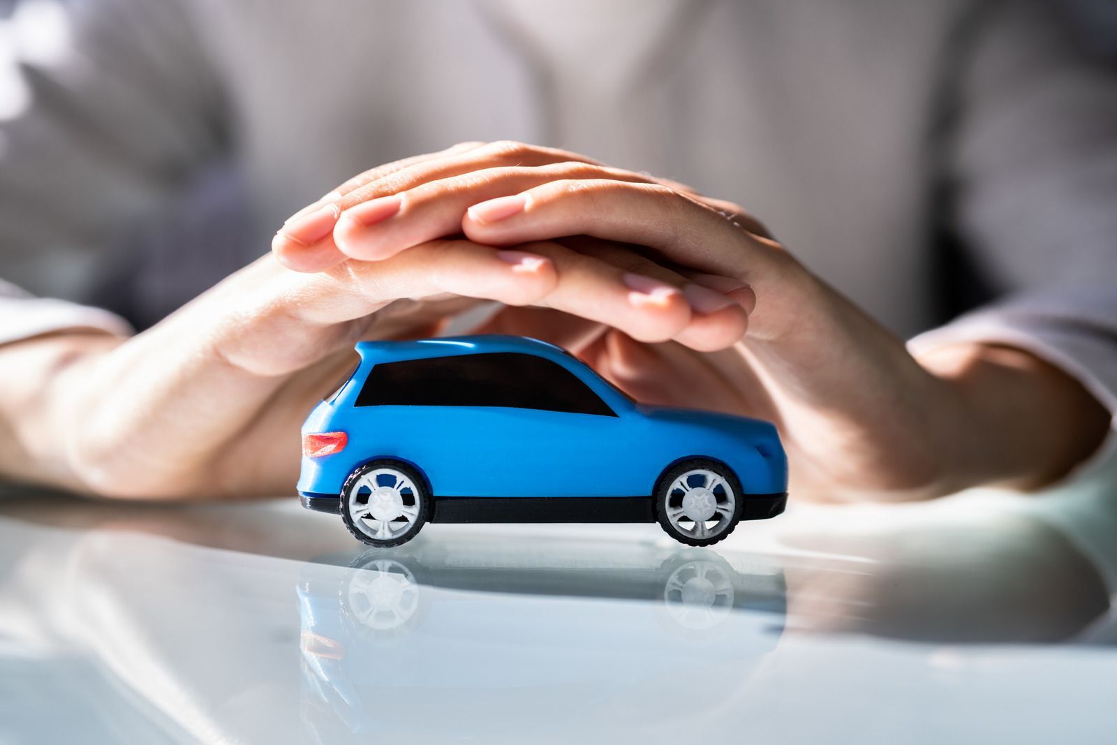 A person is holding a blue toy car in their hands.