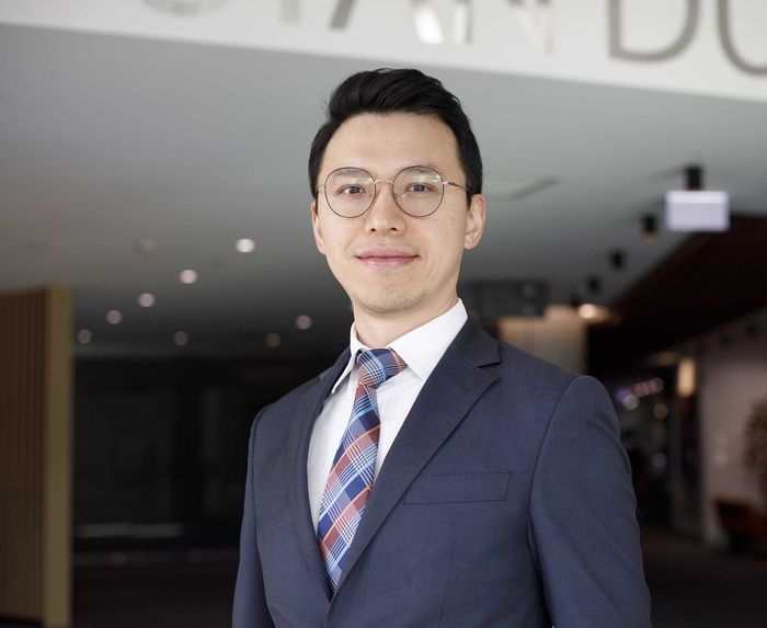 A man in a suit and tie is standing in front of a building.