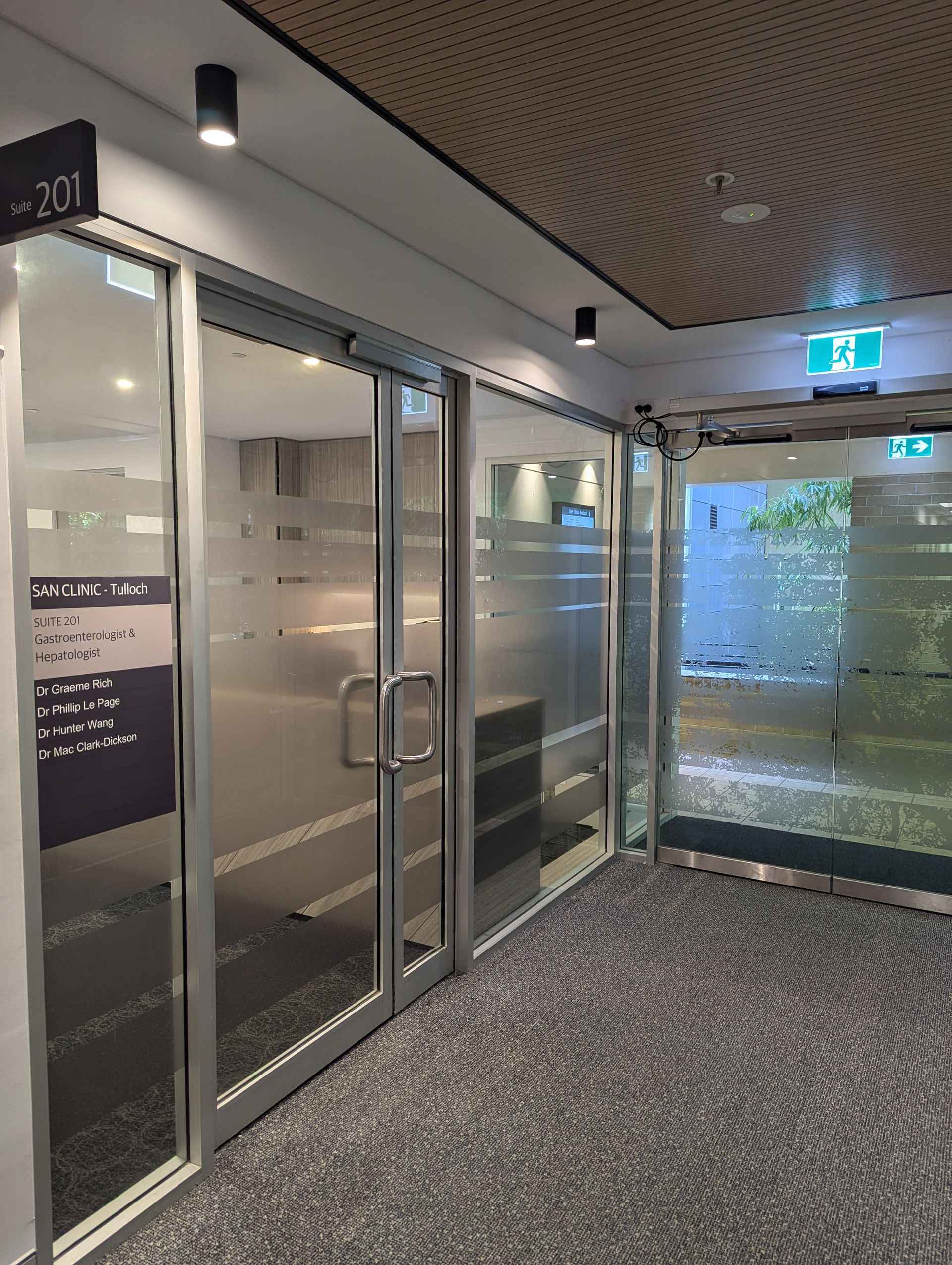 A hallway with sliding glass doors and a sign on the wall.