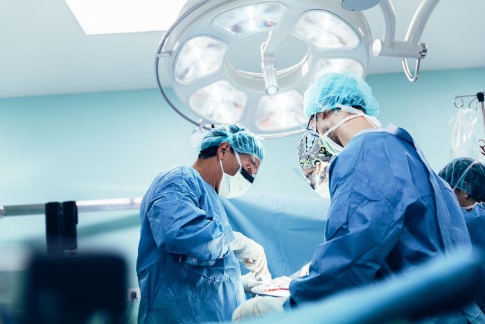 A group of surgeons are operating on a patient in an operating room.